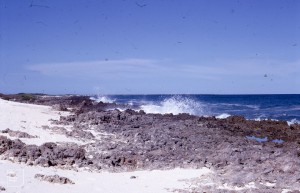 Waves scour sand from seaward side of rocks and deposit it on landward.